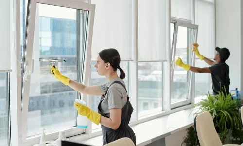 young-female-cleaner-workwear-washing-large-windows-openspace-office